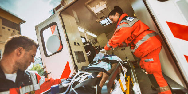 Paramedic team pushing stretcher with injured person towards ambulance. Paramedic team pushing stretcher with injured person towards ambulance.